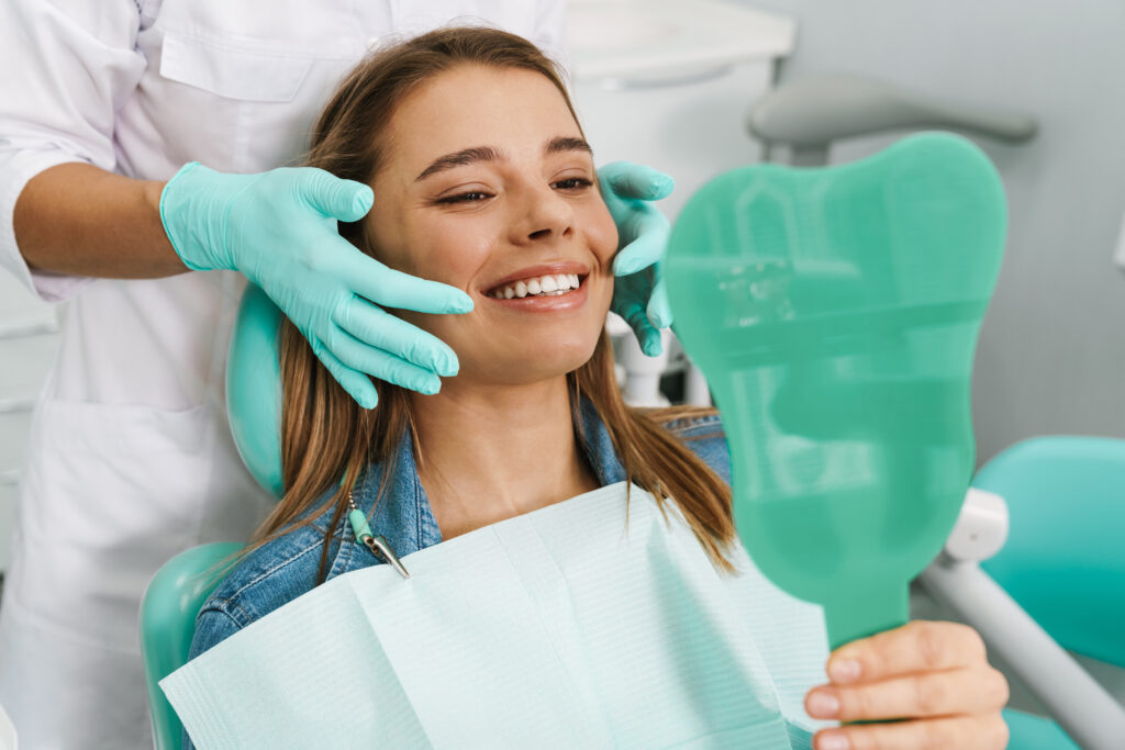 European young woman smiling while looking at mirror in dental c